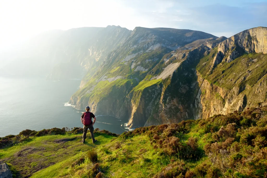View of a man looking at the view while standing on a cliff.