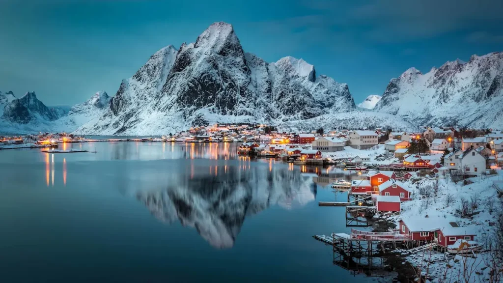 View of snow-covered village and mountain reflections in Norway.