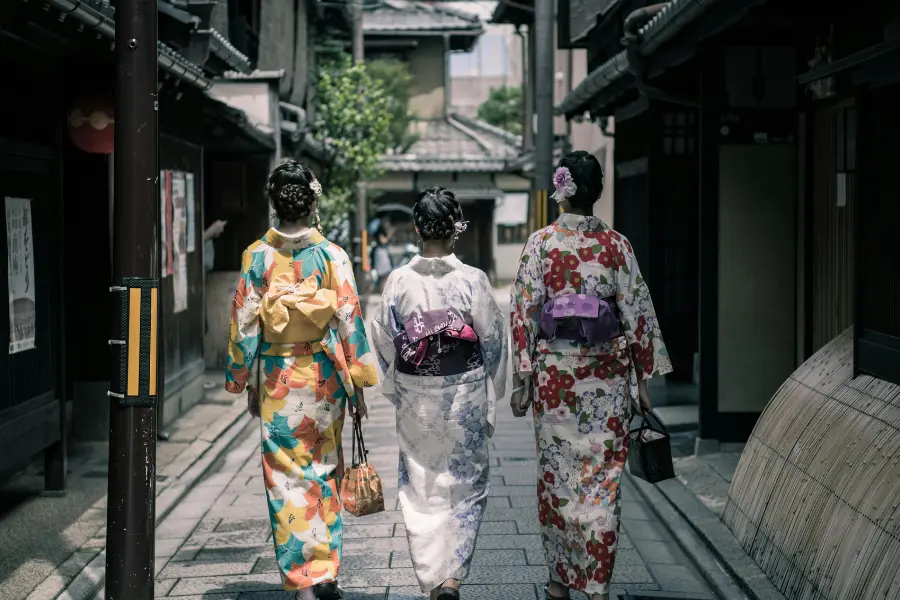 3 Japanese women wearing traditional Kimonos and walking together.