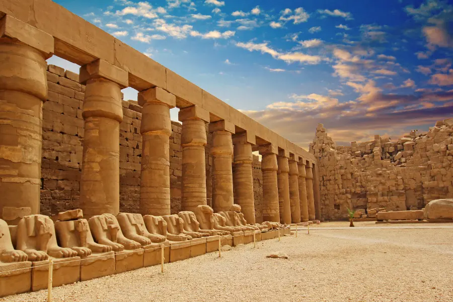 Stone columns and seated statues lining a walkway at the Karnak Temple in Luxor, showcasing ancient Egyptian architecture